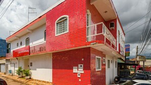 A two-story building with a red tiled facade, a balcony, and a visible sign that reads "HOTEL BRISA TROPICAL". - Tropical Brisa (São Sebastião)