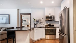 Une cuisine moderne avec des armoires blanches, des appareils en acier inoxydable et un plancher en bois.