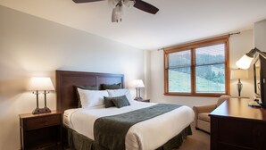 A neatly arranged bedroom with a large bed, two bedside tables with lamps, a ceiling fan, and a window with blinds. - Zephyr Mountain Lodge, Condo | 2 Bedroom (Select-Rated Condo 2409) (Winter Park)