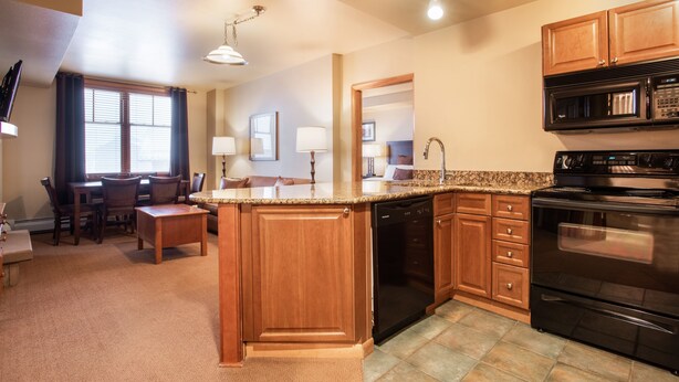 A kitchen with wooden cabinets, a black dishwasher, and a stove. - Zephyr Mountain Lodge, Condo | 4th Floor Tucked Into The Woods Ski-In/Ski-Out (Select-Rated Condo 1402) (Winter Park)
