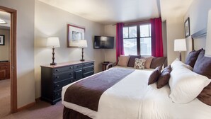 A hotel room with a large bed, a dresser, a TV, and a window with curtains. - Zephyr Mountain Lodge, Condo | 4th Floor Tucked Into The Woods Ski-In/Ski-Out (Select-Rated Condo 1402) (Winter Park)