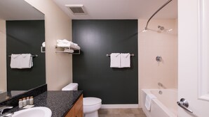A modern bathroom with a sink, toilet, and bathtub. There are towels on the wall and a shelf with toiletries. - Fraser Crossing/Founders Pointe, Condo , Ski Slope View (Premium-Rated Condo 4340) (Winter Park)