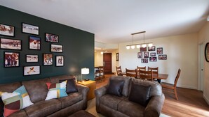 A living room with two brown sofas, a coffee table, and a dining area with wooden chairs and a table. - Fraser Crossing/Founders Pointe, Condo , Ski Slope View (Premium-Rated Condo 4340) (Winter Park)