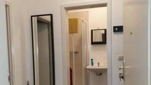 Ein Hotelzimmer mit einem großen Spiegel, einem Badezimmer mit Waschbecken und Handtuch sowie einem gemusterten Teppichboden.