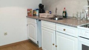 Eine Küche mit weißen Schränken, einer Granitarbeitsplatte, einer Kaffeemaschine und einem Spülbecken.