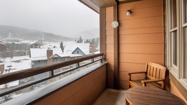 A balcony with a wooden chair and a clock on the wall. - Zephyr Mountain Lodge, Condo , 2 bedroom (Select-Rated Condo 1604) (Winter Park)