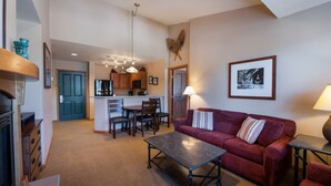 A spacious living area with a red sofa, a coffee table, and a kitchen in the background. - Zephyr Mountain Lodge, Condo , 2 bedroom (Select-Rated Condo 1604) (Winter Park)