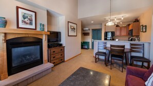 A living room with a fireplace, a TV, and a dining area with chairs and a table. - Zephyr Mountain Lodge, Condo , 2 bedroom (Select-Rated Condo 1604) (Winter Park)