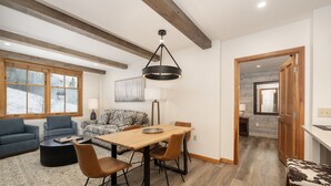Un salon moderne avec une table à manger en bois, des sièges confortables et de grandes fenêtres.