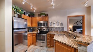 A modern kitchen with stainless steel appliances, wooden cabinets, granite countertops, and a built-in oven. - Zephyr Mountain Lodge, Condo | 2 Bedroom (Select-Rated Condo 2406) (Winter Park)