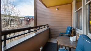 A balcony with a wooden bench, a table, and two chairs. - Zephyr Mountain Lodge, Condo | 2 Bedroom (Select-Rated Condo 2406) (Winter Park)