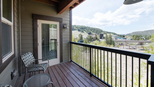 A wooden deck with a black railing, a door with a window, and a chair. - Fraser Crossing/Founders Pointe, Condo , 2 bedroom (Premium-Rated Condo 3506) (Winter Park)