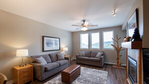 A modern living room with two sofas, a coffee table, a fireplace, and a ceiling fan. - Fraser Crossing/Founders Pointe, Condo , 2 bedroom (Premium-Rated Condo 3506) (Winter Park)