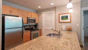 A kitchen with granite countertops, stainless steel appliances, wooden cabinets, a microwave, a stove, and a sink. - Fraser Crossing/Founder Pointe, Townhome style Condo | Gondola Acess (Value-Rated Condo 3229) (Winter Park)