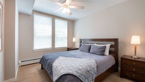 A bedroom with a bed, nightstands, a ceiling fan, and a window with blinds. - Fraser Crossing/Founder Pointe, Townhome style Condo | Gondola Acess (Value-Rated Condo 3229) (Winter Park)