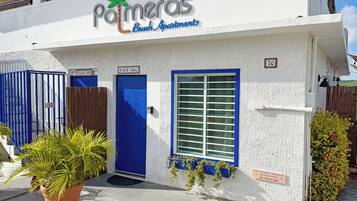 Un immeuble avec une enseigne indiquant « Palmeras Beach Apartments » et une porte bleue portant l’inscription « Vista Lago ».