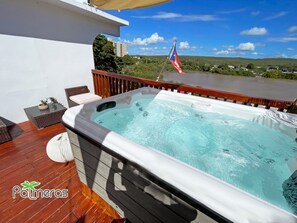 A hot tub on a wooden deck with a view of a river and hills. - Lake View Apt with Jacuzzi and Terrace in Playa Santa (Ensenada, Guanica)