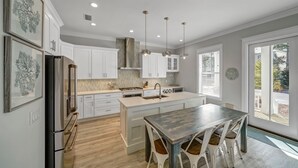 A modern kitchen with white cabinets, a central island, and pendant lighting. - Coastal Luxury on 30A: 4br/4ba: golf cart, walk to beach, shopping, & dining!   (Santa Rosa Beach)