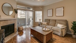 A living room with a fireplace, a sofa, a coffee table, and a ceiling fan. - Cozy 1-Bdrm Scottsdale Condo next to pool (Scottsdale)