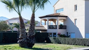 A two-story house with a balcony, surrounded by palm trees and a well-maintained lawn. - Les Reflets by Interhome (Saint Cyprien)