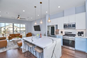 A modern kitchen with a large island, stainless steel appliances, and pendant lighting.