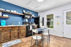 Une cuisine avec des meubles de rangement en bois, une cuisinière, un four à micro-ondes et une petite table à manger avec des chaises.