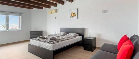 Un dormitorio moderno con cama, mesitas de noche, un sofá y una ventana.