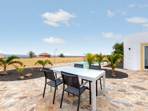An outdoor patio with a table and chairs, a pool, and a view of the ocean.