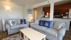 A living room with two grey-striped sofas, a white coffee table, and a patterned rug. - IT'S A SHORE THING ☀️3BR Oceanfront Condo in Duck w/Community Pool☀️ (Duck)