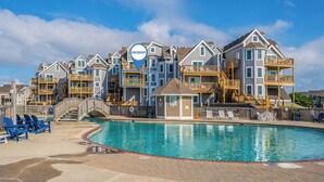 A beachfront hotel with multiple balconies, a swimming pool, and a lifeguard tower. - IT'S A SHORE THING ☀️3BR Oceanfront Condo in Duck w/Community Pool☀️ (Duck)