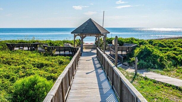 A wooden boardwalk leading to a gazebo with benches on either side, surrounded by greenery. - IT'S A SHORE THING ☀️3BR Oceanfront Condo in Duck w/Community Pool☀️ (Duck)