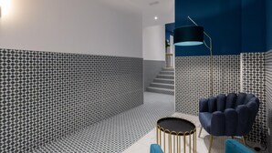 A modern interior with patterned walls, a round gold table, and a blue armchair.