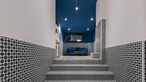 A staircase with patterned tiles leading to a seating area with a blue sofa and a small table.