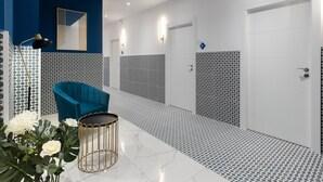 A modern bathroom with a blue accent wall, patterned tiles, and a blue chair.