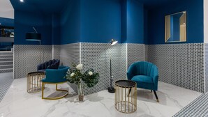 A modern room with a blue accent wall, a large mirror, and a blue armchair.