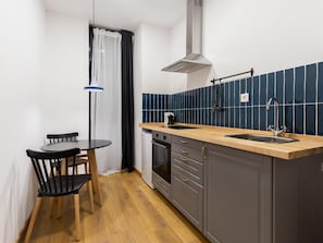 Een koelkast, een oven, kookgerei, borden en bestek, een eettafel