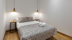 A neatly made bed with a patterned bedspread and two pillows, flanked by bedside tables with lamps. - Hotelito Boutique Valencia Estación 3 (Valencia)