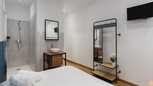 Ein modernes Badezimmer mit Dusche, Waschbecken und einem großen Spiegel.