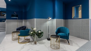 Ein modernes Zimmer mit blauer Akzentwand, einem großen Spiegel und einem blauen Sessel.