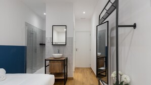 Een moderne badkamer met een grote spiegel, een wastafel en een douche.
