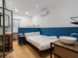 A modern hotel room with a bed, a large white sink, and a blue accent wall.
