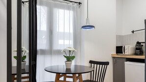 Eine kompakte Küche mit Esstisch, Stühlen, einer Hängelampe und einem Blumentopf.