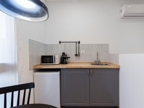 A compact kitchen with a microwave, coffee maker, and sink.