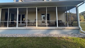 Une véranda abritée, dotée de plusieurs coins salon et offrant une vue sur un paysage verdoyant.