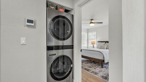 Ein Waschraum mit zwei Geräte mit Frontlader sowie Trockner, einem Thermostat und einem Deckenventilator.