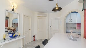 A dining area with a white table, black chairs, a mirror, and a kitchen visible through an archway. - ARTE DE LUZ - Fantastic apartment next to the golf course and with a shared pool in Calaho (Mijas)