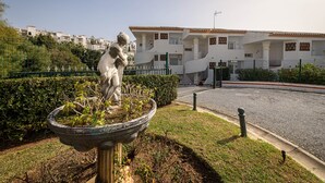 A statue in a garden with a white building in the background. - ARTE DE LUZ - Fantastic apartment next to the golf course and with a shared pool in Calaho (Mijas)