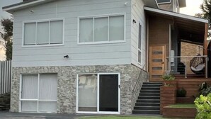 A modern two-story house with a stone facade, a front garage, and a well-maintained lawn. - Your Perfect Retreat with Unlimited WiFi, Netflix,Steps Away from Beach & Shops  (Rosebud)