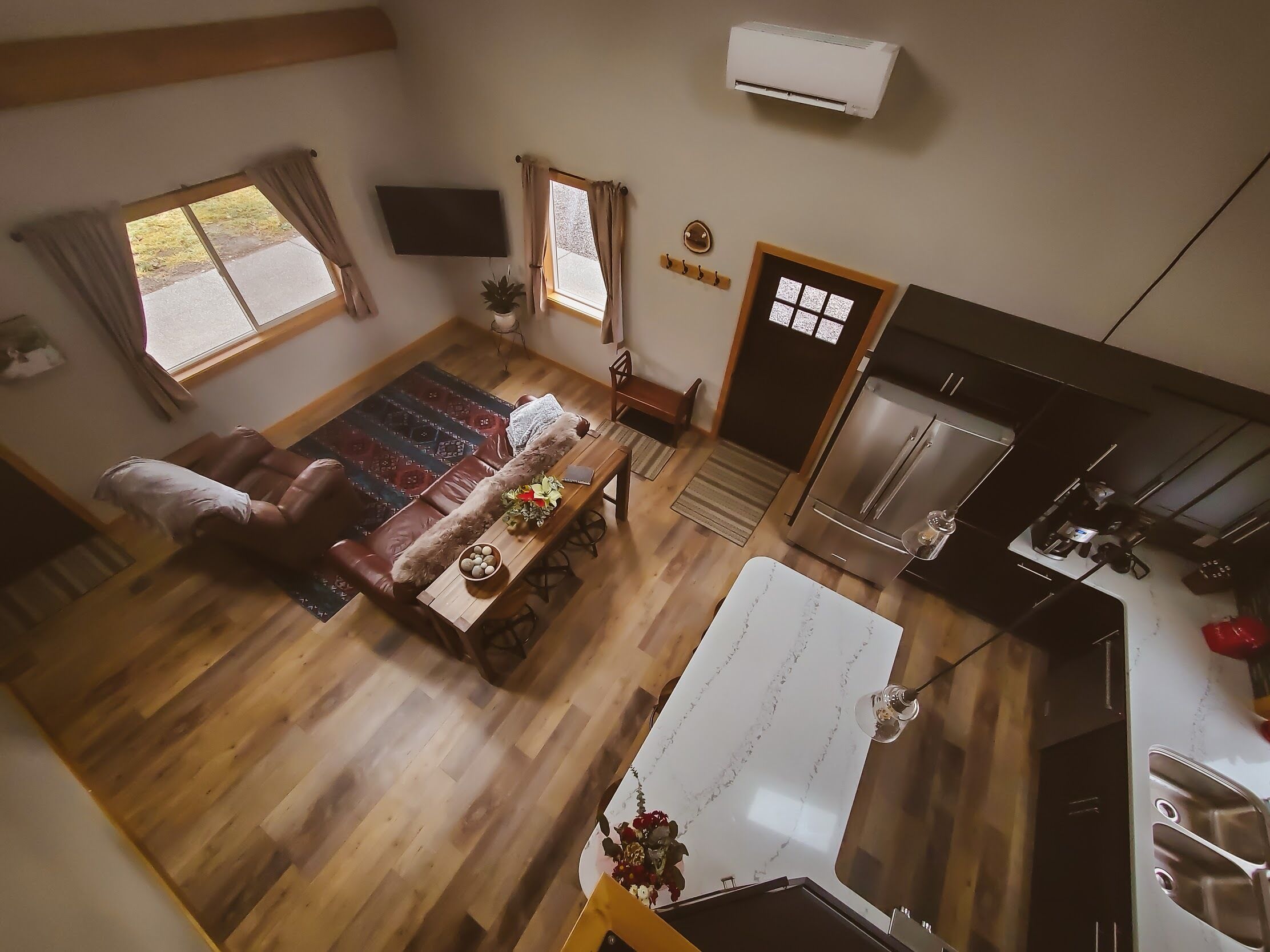 A spacious living room with a sofa, a dining table, and a kitchen area with a refrigerator and sink.