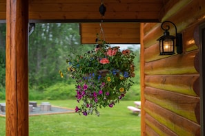 A hanging flower basket with a variety of flowers and a wall-mounted lantern.